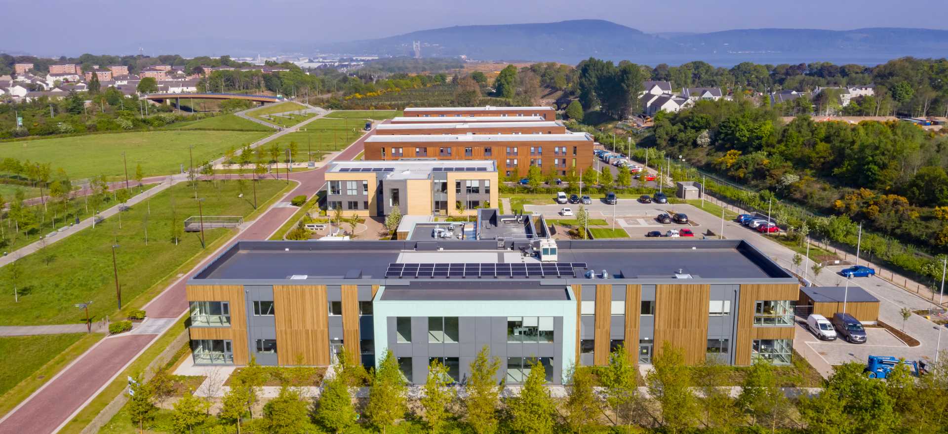 Aerial view over Inverness Campus with red brick buildings and lush green land parks